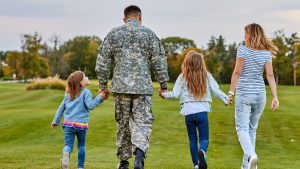 A veteran in fatigues walking through a field with his family