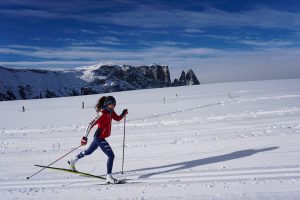 A woman wearing a red jacket, skiing on the snow.