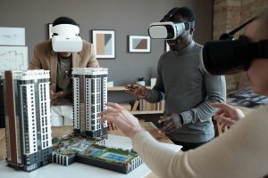 Three people interacting with an apartment model on a desk using the Virtual Reality eye gear.