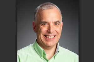 A headshot of John Piorkowski wearing a light green shirt.