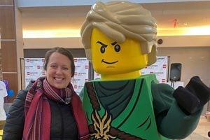 Kathleen Flynn poses for a photo next to a giant LEGO person.
