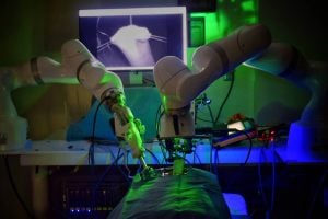 The STAR surgical robot performs a demonstration surgery in a dark room with a monitor showing a close-up of the procedure.