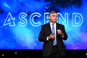 A photo of David Van Wie delivering a talk at the AIAA ASCEND Forum in front of a blue background that reads "ascend"