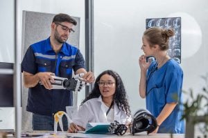 3 biomedical engineers at a table working on prosthetic hand prototypes.