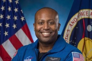 Portrait of andre douglas standing in front of an American flag and a NASA flag.